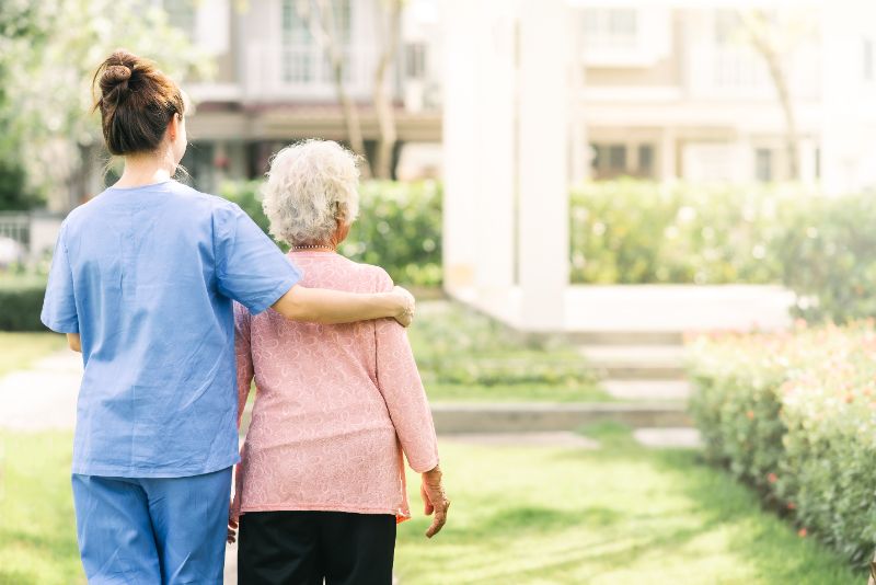 Caregiver กำลังดูแลผู้ป่วยสูงอายุบนเตียงอย่างใกล้ชิด
